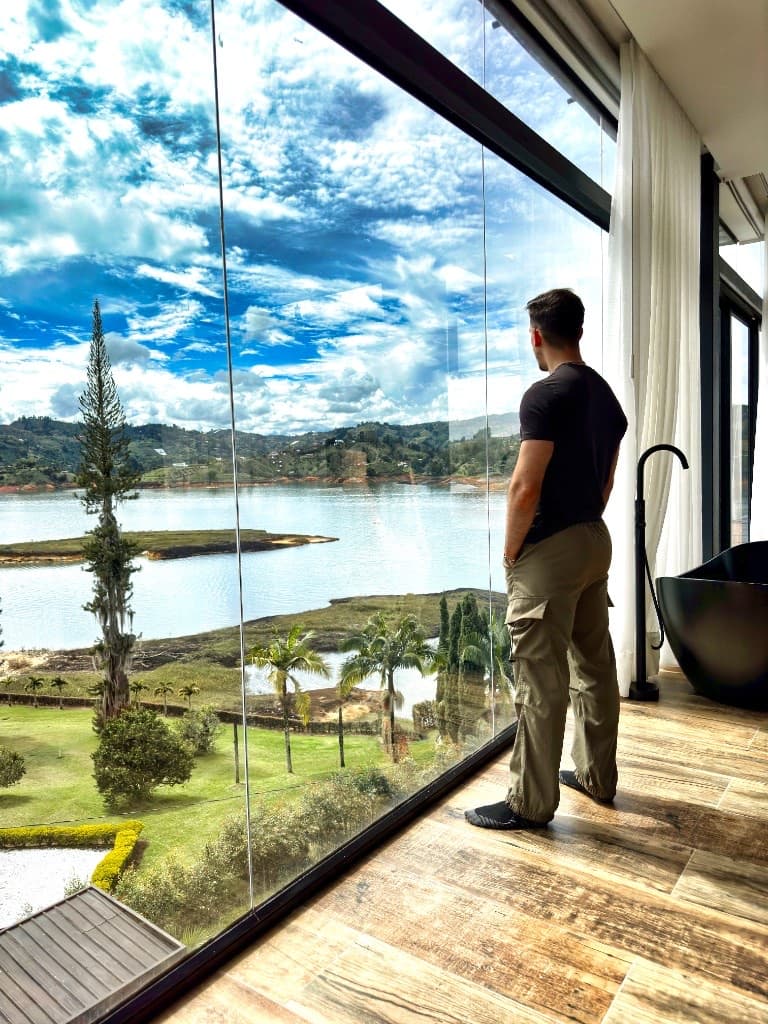 Michael looking through floor-to-ceiling windows at lake and green hills